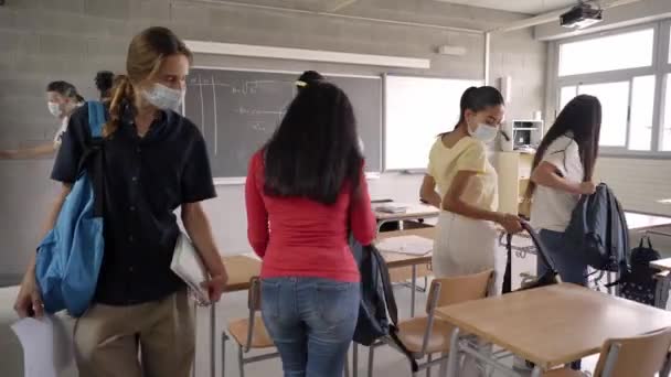 先生と高校生は保護マスクをした教室に入ります。大流行の学校に戻り. — ストック動画