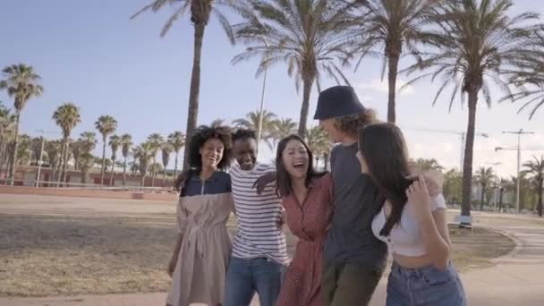 Movimiento lento de un grupo de amigos multiétnicos divirtiéndose. Jóvenes estudiantes caminando riendo y abrazándose celebrando alegremente. — Vídeo de stock