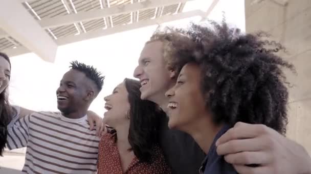 Grupo de pessoas, sorrindo e felizes por estarem juntos. Uma menina latina abraçando seus amigos, um menino afro-americano e um menino asiático. Conceito de estudantes multiétnicos. — Vídeo de Stock