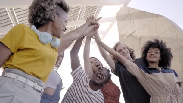 Grupo de jóvenes apilándose de la mano. Grupo multiétnico de estudiantes celebrando al aire libre. — Vídeos de Stock