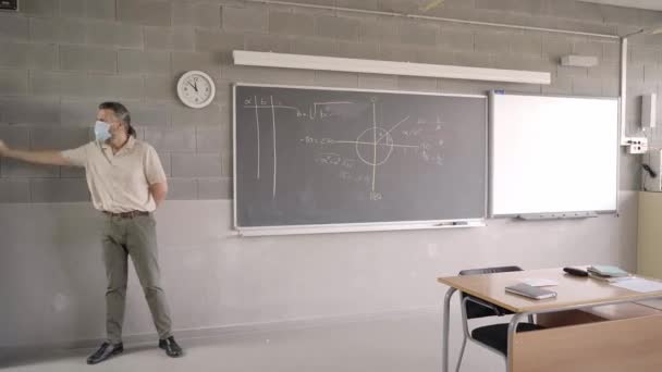 L'enseignant accueille les élèves qui entrent dans la salle de classe portant des masques de protection. Nouvelle normalité dans l'éducation, prise de mesures de sécurité contre le coronavirus covid-19. — Video