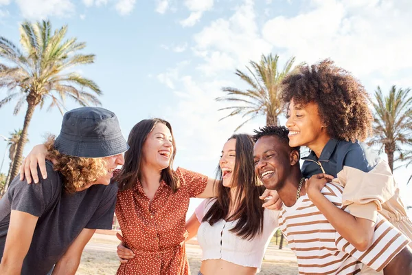 Grupo de jóvenes riendo y divirtiéndose fuera de un pueblo de playa. Concepto de verano, multiétnico, integración, amistad. — Foto de Stock