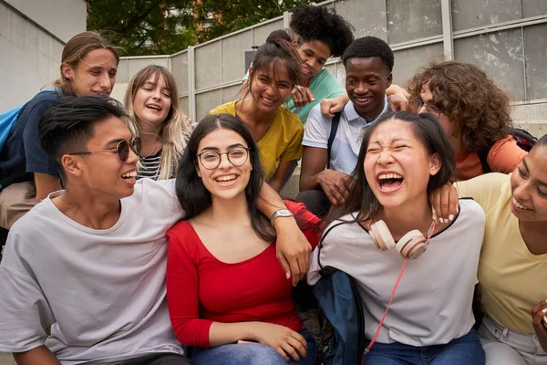 A girl surrounded by classmates looking at a smiling camera. Happy students in high school. — Stock Photo, Image