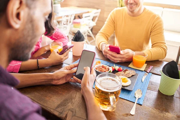 Close-up of unrecognizable man using his cell phone in a restaurant, cafe. Group of friends having fun sharing online. — Stock Photo, Image
