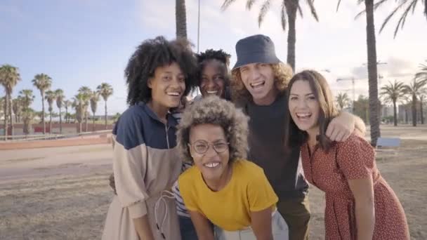 Jóvenes amigos mirando la cámara sonriente. Grupo de personas divirtiéndose al aire libre. Estilo de vida moderno de los jóvenes multiculturales. — Vídeo de stock