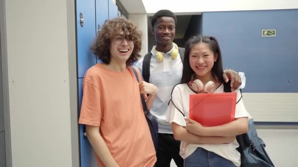 Retrato de tres estudiantes multirraciales mirando a la cámara sonriendo en una escuela secundaria. — Vídeo de stock