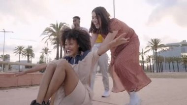 Bir grup genç şehirde kaykayla eğleniyor. Gülen siyah kız kaykayın üzerinde oturuyor ve beyaz kız tarafından itilip kakılıyor. Kızlar.