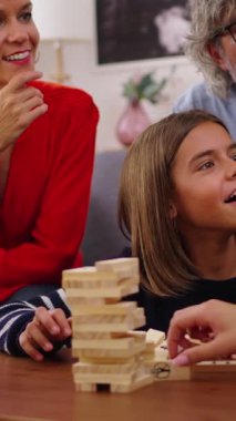 Dikey. Heyecanlı çok nesilli aile toplantısı evde Jenga oynuyor. Beyaz insanlar birlikte oyun oynayarak ev yaşamlarını sürdürüyorlar. Bir kadın kuleden odun parçası alıyor ve düşüyor.