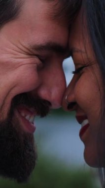 Dikey. Alınları birbirine değmiş, gözleri kapalı, gülümseyen, şefkat, güven ve derin bir bağ kuran ırklar arası bir çiftin yakın çekimi..