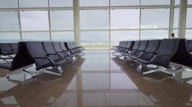 Afrikalı milenyum kadını, kamera kendisine doğru ilerlerken, parlak bir havaalanı terminalinde yürürken cam mimarisini, yansımalarını ve kasıtlı seyahat havasını ön plana çıkarıyor..