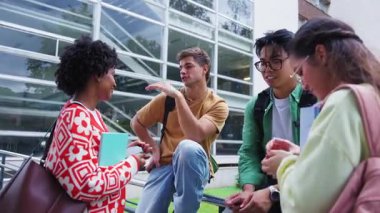 Çeşitli öğrenciler kampüsteki modern bir cam binanın yanında sohbet ediyorlar. Arkadaşlar dinlerken bir akıllı telefonu kontrol ediyorlar. Ders sonrası keyfi an, çalışma hayatını ve takım çalışmasını ön plana çıkarıyor..