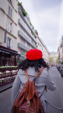 Dikey. Gülümseyen Afrikalı bin yıllık kadın el ele tutuşuyor ve arka planda Eyfel Kulesi 'ne liderlik ediyor. Geniş açılı seyahat portresi canlı şehir atmosferi ve sıcak güneş ışığı ile.