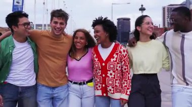 Çeşitli çok kültürlü genç bin yıllık arkadaşlar şehir palmiyeleri boyunca kucaklaşıyorlar. Üniversiteliler kampüse giderken gülerek dışarı çıkıyorlar. Neşeli öğrencileri bir araya getirin..