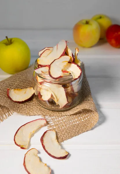 Dried Dehydrated Apple Chips in Glass Jar with Fresh Apple on white background