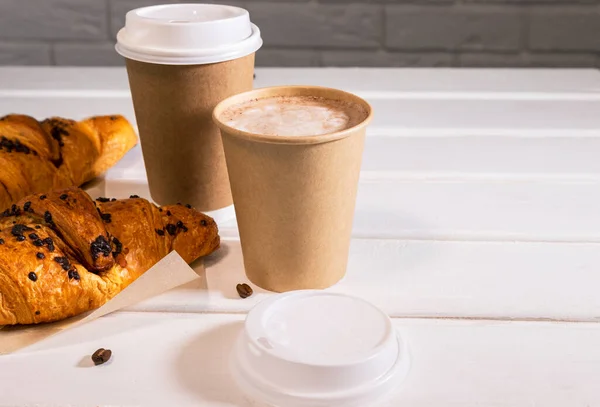 Take away coffee, fresh croissant and coffe beans on wooden background, Copy Space