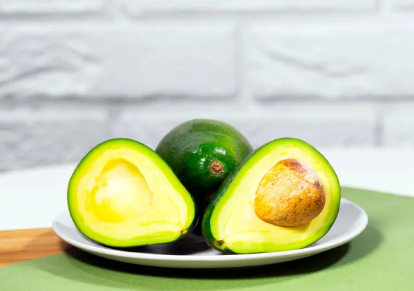 Halva mogna Avokado på skål serveras på bord, Grön och vit bakgrund, Friska fet mat, Keto diet — Stockfoto