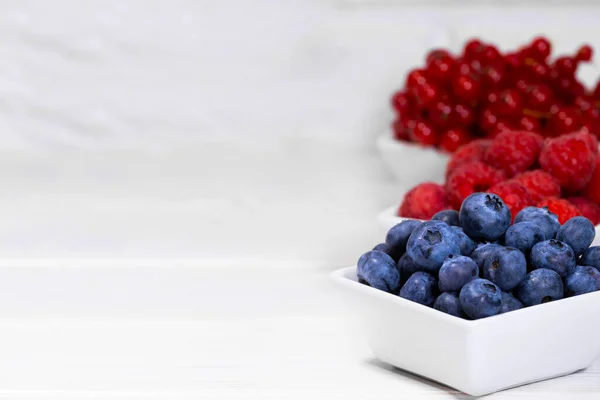 Fresh Raw Berries in white ceramic bowl on white background. Space for text. Red Currant, Raspberry and Blueberry, Summer Fruits, Antioxidant, Copy space — Stock Photo, Image