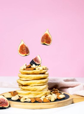 Pembe arka planda incirli krep ve fındıklar, Geleneksel Amerikan Sağlıklı Kahvaltısı, Copyspace, Dikey Çözünürlük.