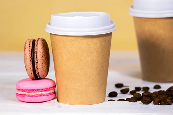 Coffee to go in paper eco cup with chocolate french macaroon on wooden and light orange background, Fast food, Copyspace, Caffeine Drink take away