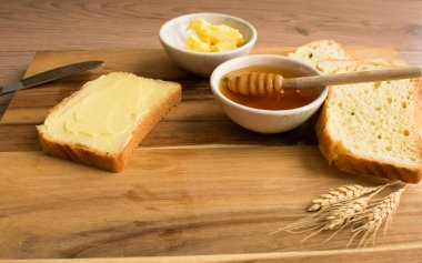 Ahşap zemin üzerinde bal ve tereyağlı ekmek.