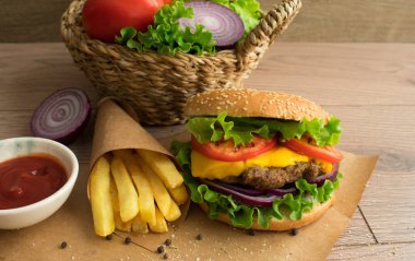 Burger and french fries on wooden background.