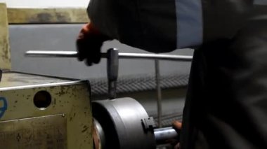 Değirmen makinesinde çalışan bir adam işlemler için bir parçayı kıskaçlar. Arka plan