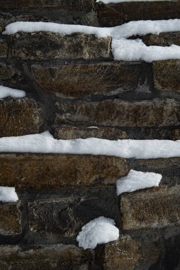 Kenarlara kar serpiştirilmiş desenli taş duvar.