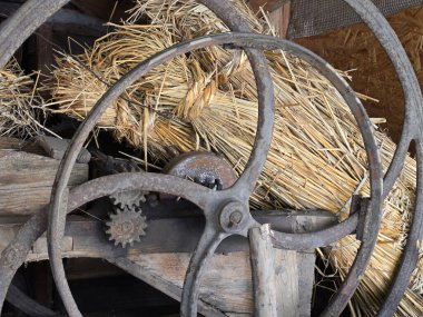 Antika tarım makinesi tekerleği ve samanlı kırsal ambarda dişliler.