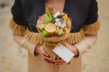 Özgün alışılmadık yenilebilir sebze ve meyve buketi kadın elinde kart ile 