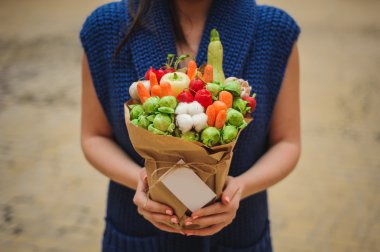 Özgün alışılmadık yenilebilir sebze ve meyve buketi kadın elinde kart ile 