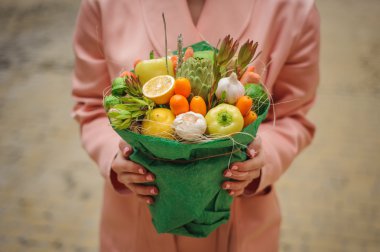 Özgün alışılmadık yenilebilir sebze ve meyve buketi kadın elinde 
