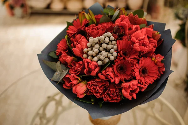 Красивый букет красных цветов с черной бумагой в руках — стоковое фото