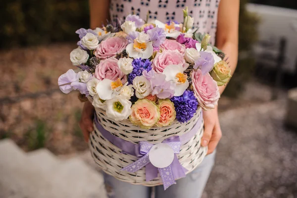 Beautiful purple  bouquet of mixed flowers in basket hold by woman — Stock Photo, Image
