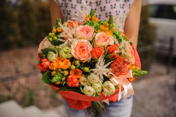 Bukett av olika orange blommor i händer — Stockfoto