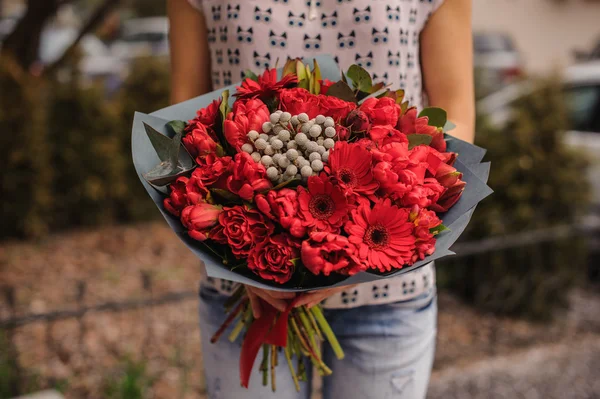Belo buquê de flores vermelhas com papel preto nas mãos — Fotografia de Stock