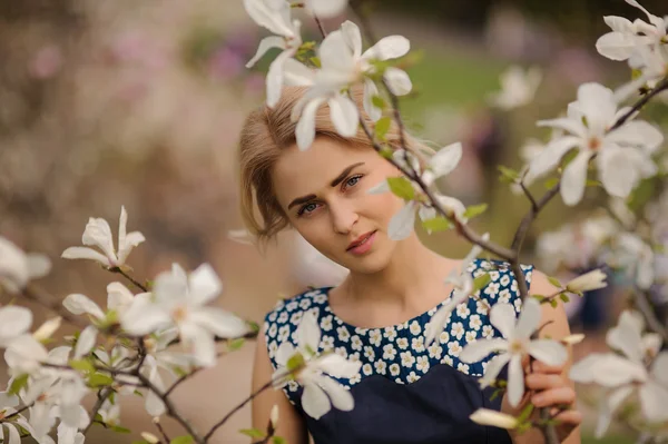 Retrato de joven hermosa modelo mujer posando en el jardín con magnolias florecientes . — Foto de Stock