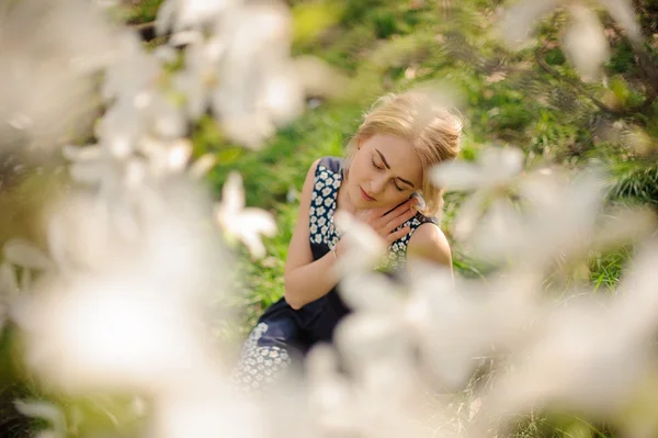 Portrait of young beautiful model woman posing in the garden with blooming magnolias. — Stock Photo, Image