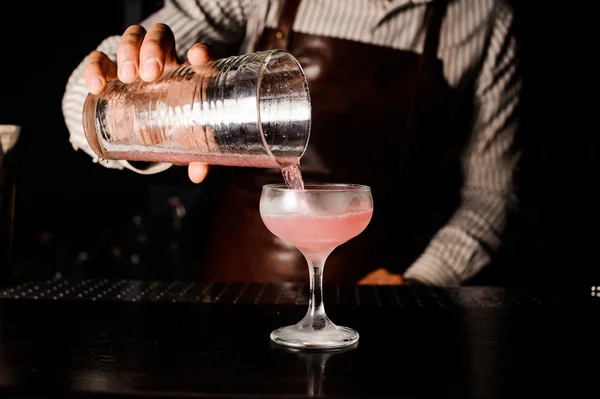 Barmann bereitet kosmopolitischen alkoholischen rosa Cocktail an der Bar vor und schenkt ihn ein. — Stockfoto