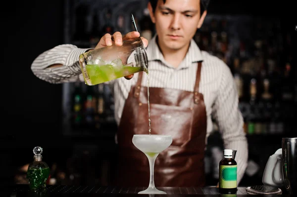 Barman pouring a cocktail into glass — Stock Photo, Image