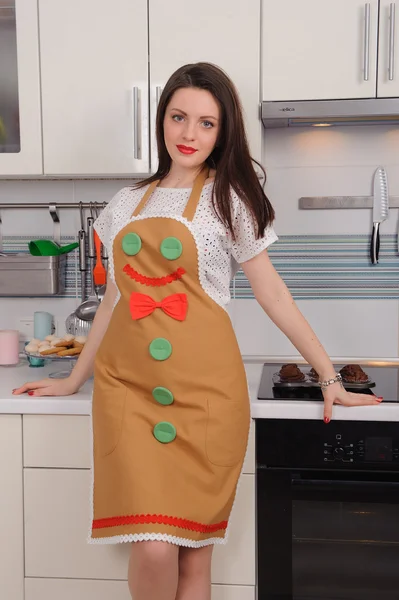 Vrouw in schort met cupcakes in keuken — Stockfoto