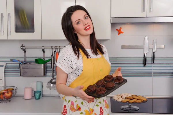 Portrait woman in apron with cupcakes in kitchen — Stock Photo, Image