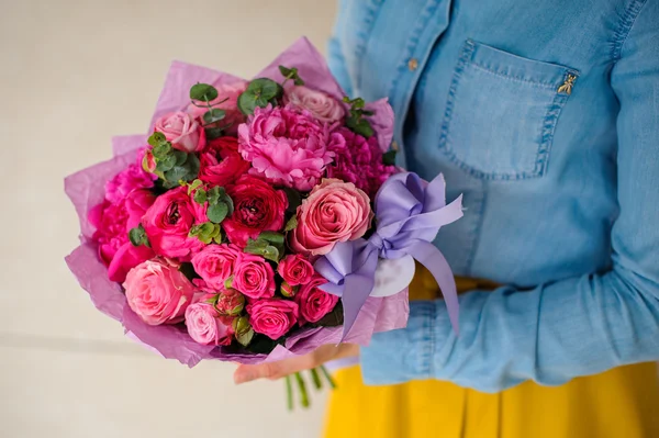 Menina segurando buquê de uma mistura de flores rosa e roxo — Fotografia de Stock