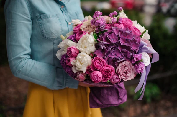 Girl holding a bouquet of purple and white flowers — Stock Photo, Image