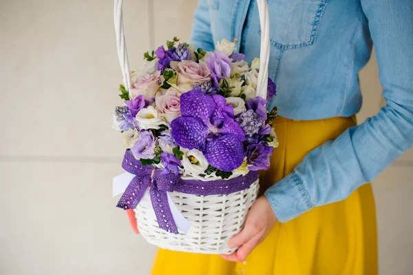 Girl holding beautiful purple bouquet of mixed flowers in basket — Stock Photo, Image
