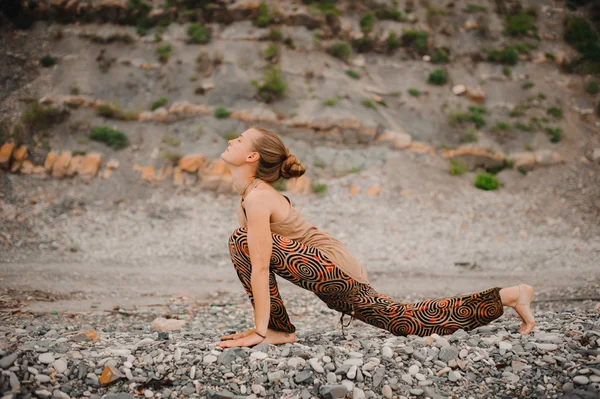 Jeune femme faisant du yoga sur un rivage rocheux. pose de chien orientée vers le haut — Photo