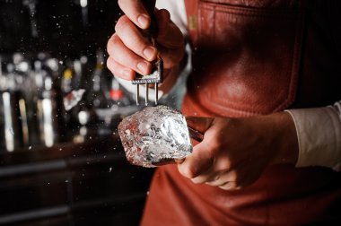 Barmen kazmayla buz kırıyor.