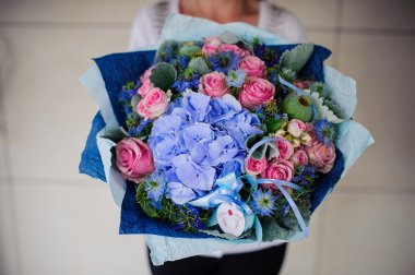 Elinde beyaz ve mavi çiçek buketi