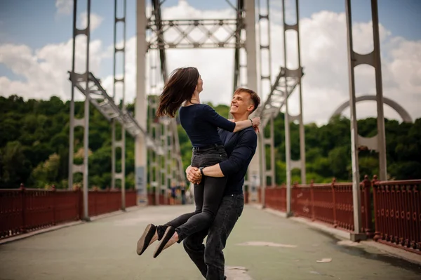 Mooie gelukkige jonge paar van man en vrouw spinnen buiten op brug — Stockfoto