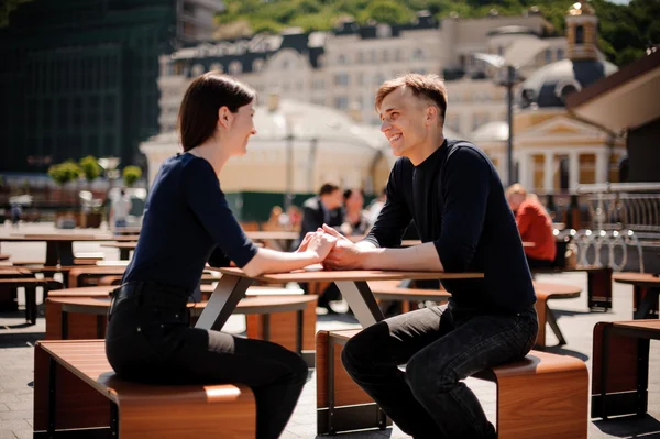 Ung, lyckliga paret leende och hålla händerna över bordet på en restaurang. — Stockfoto