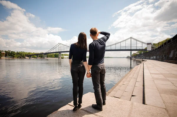 Jovem casal homem e mulher de pé na beira do rio — Fotografia de Stock
